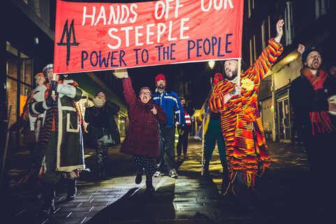 A group of protestors holding a sign that reads ‘Hands off our steeple, power to the people’.