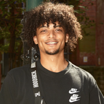 An individual with semi-long brown hair, wearing all black and looking at the camera.